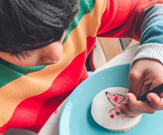 Boy decorating icing with cake pen